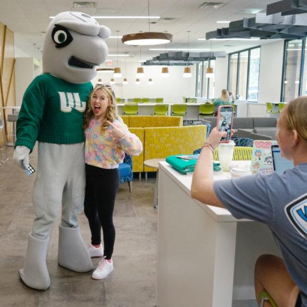 A femaie student posing for a social media selfie with JU's mascot
